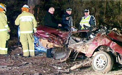 Emergency service workers inspect the car wreck in which four people died on Saturday. Emergency service workers inspect the car wreck in which four people died on Saturday.
